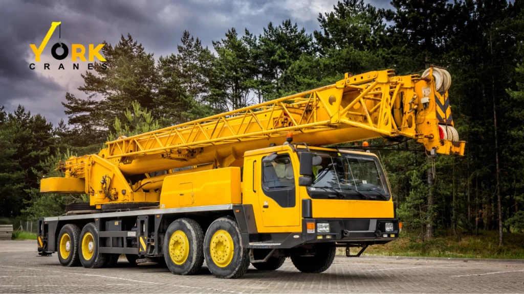 A mobile crane with a telescopic boom lifting construction materials to show what a mobile crane.